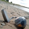 Crossgolfschläger und Ball am Strand