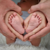 Florian und seine Frau halten die Füße ihres Babys in den Händen