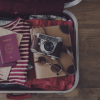Geöffneter Koffer mit Kleidung, Reisedokumenten und einer Kamera