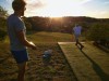 Zwei junge Männer spielen Disc Golf im Sonnenuntergang Zwei junge Männer spielen Disc Golf im Sonnenuntergang