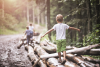 Kinder spielen im Wald, laufen auf liegenden Baumstämmen